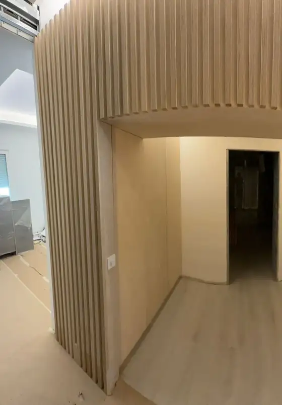 Volumen curvo revestido de listones de madera a medida en una vivienda de Madrid
