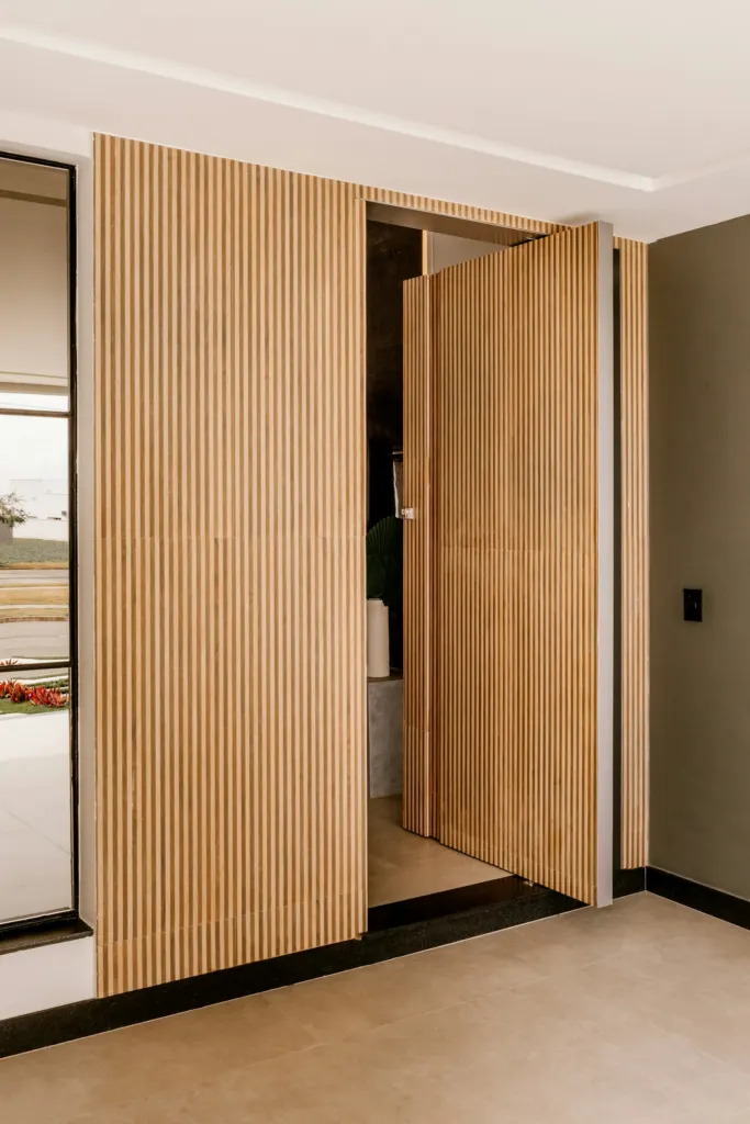 Puerta pivotante de gran altura revestida de listones de madera