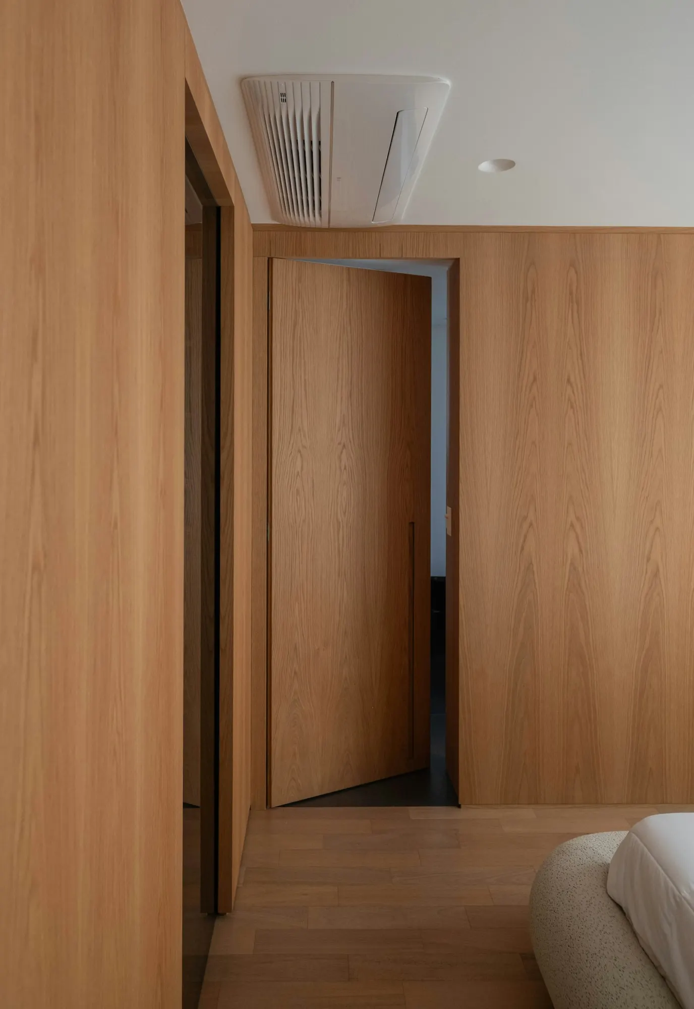 Puerta de paso de suelo a techo en chapa de roble, enrasada con un revestimiento de madera